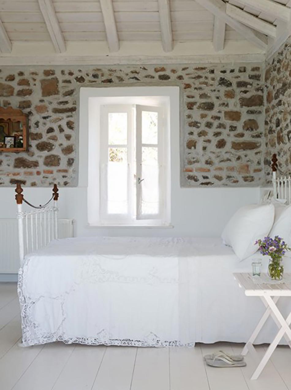 Chambre rustique au plafond en bois et mur en pierres